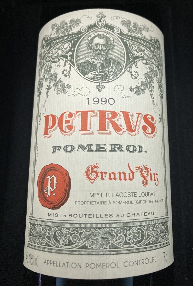 페트뤼스 1990 라벨, 열쇠를 든 인물 그림 아래 PETRVS, POMEROL, Grand Vin이 적혀 있다